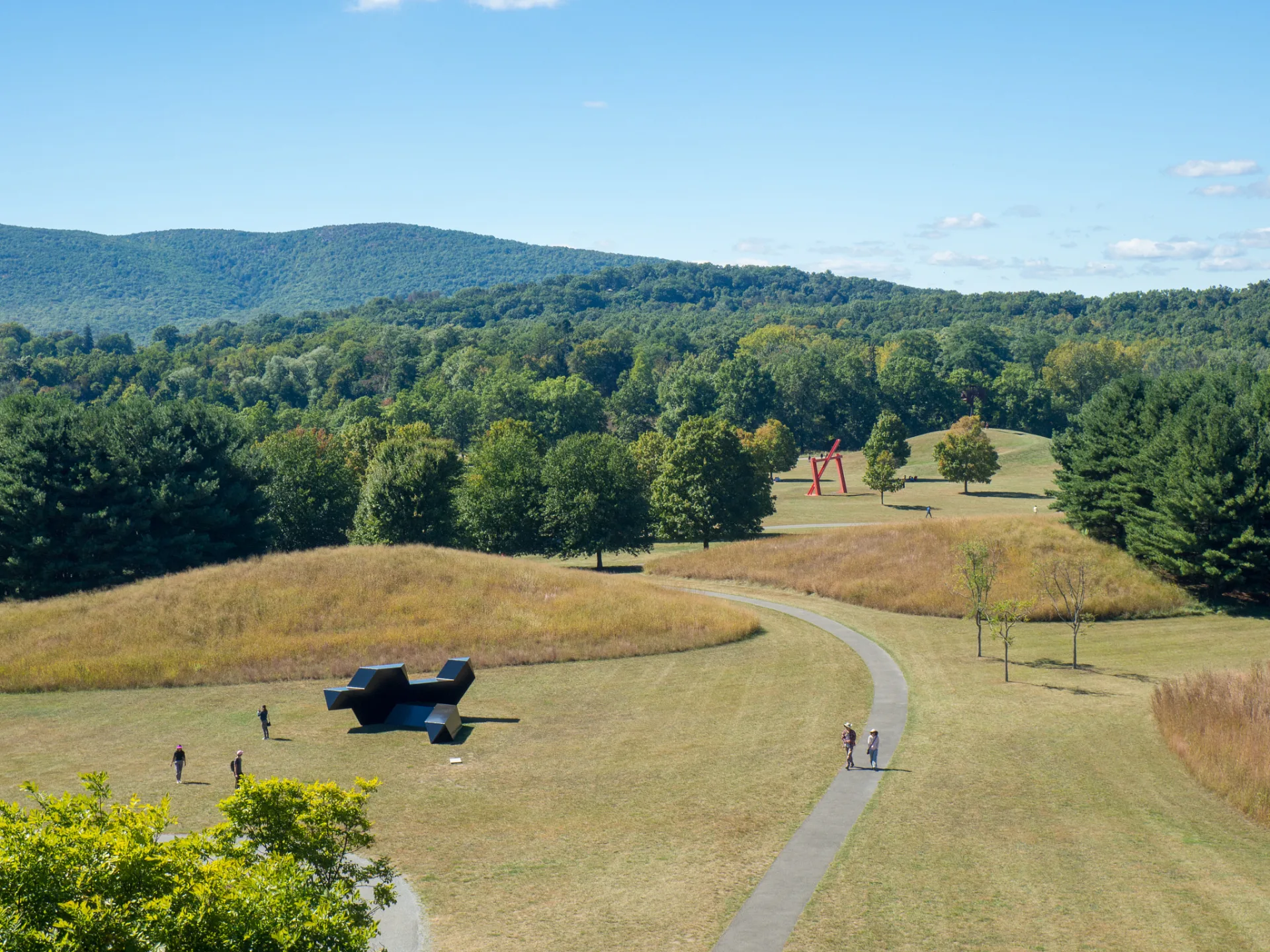 Mown paths winding between sculptures across the meadows of Storm King Art Center, with the Hudson Highlands behind
